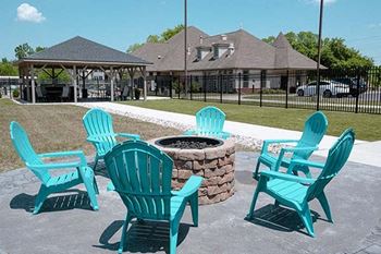 four blue adirondack chairs around a fire pit